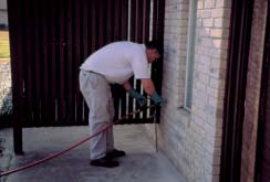 Person injecting termiticide in foundation.