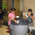 Students tacking their trash to a trash container 