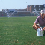 Image of man on turfgrass with sprinklers in the background