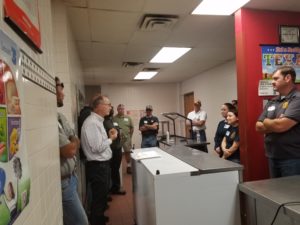 Several people standing in a school kitchen serving area